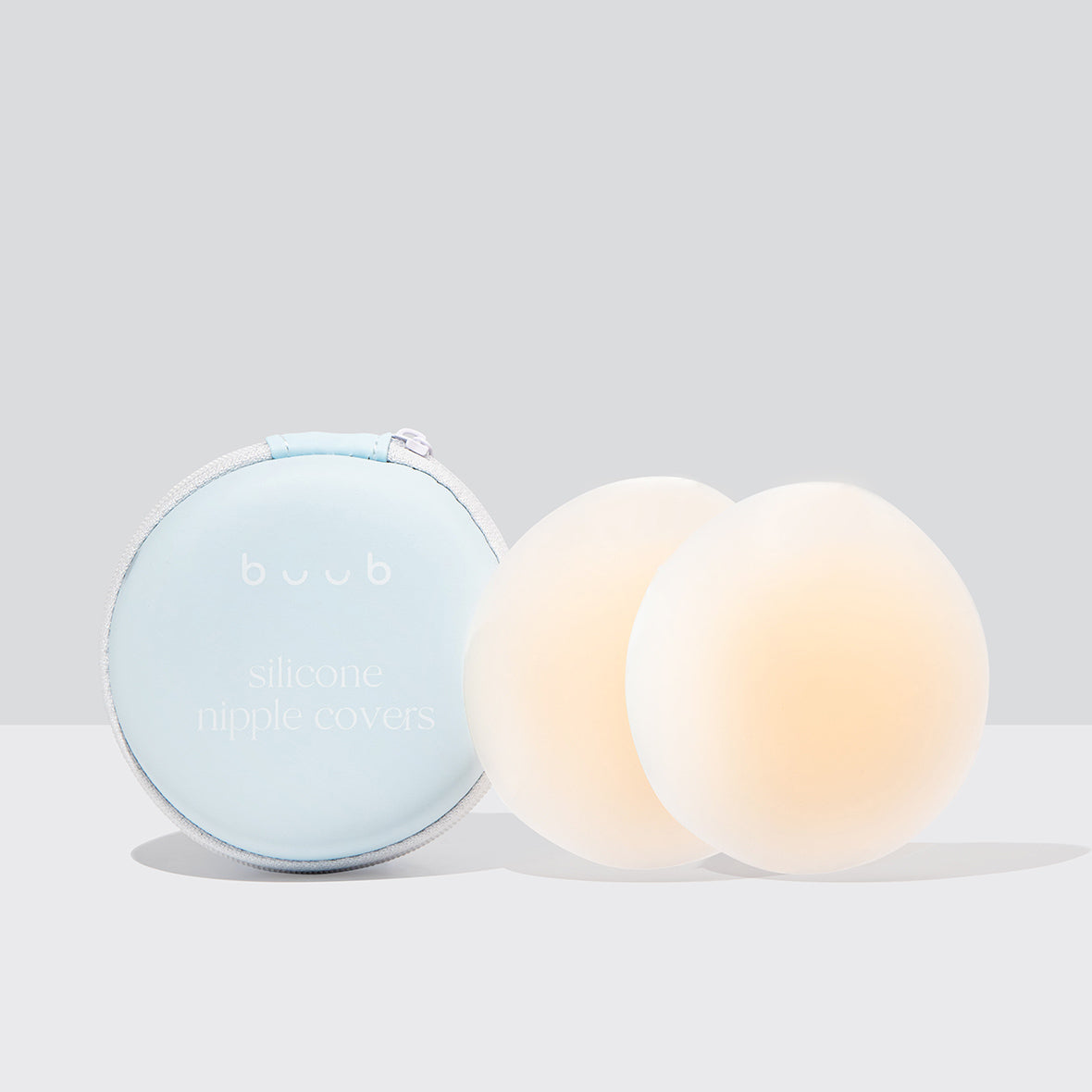 A pair of 8cm Buub reusable adhesive silicone nipple covers in a light nude shade. These stick-on pasties come with a stylish light blue zippered travel case.