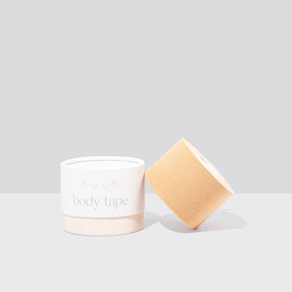 A roll of standard width Buub Body Tape in nude, suitable for lighter skin tones. The adhesive bra alternative is shown with its cylindrical packaging against a neutral backdrop.