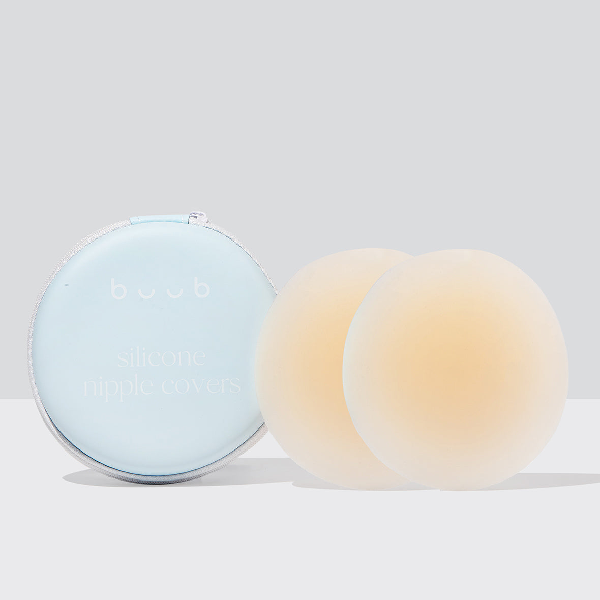 A pair of large 10cm Buub non-adhesive silicone nipple covers in nude for maximum coverage. The reusable pasties are shown with their cream-coloured storage case.